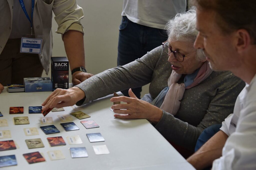 Une personne âgée joue à un jeu de cartes avec un homme.